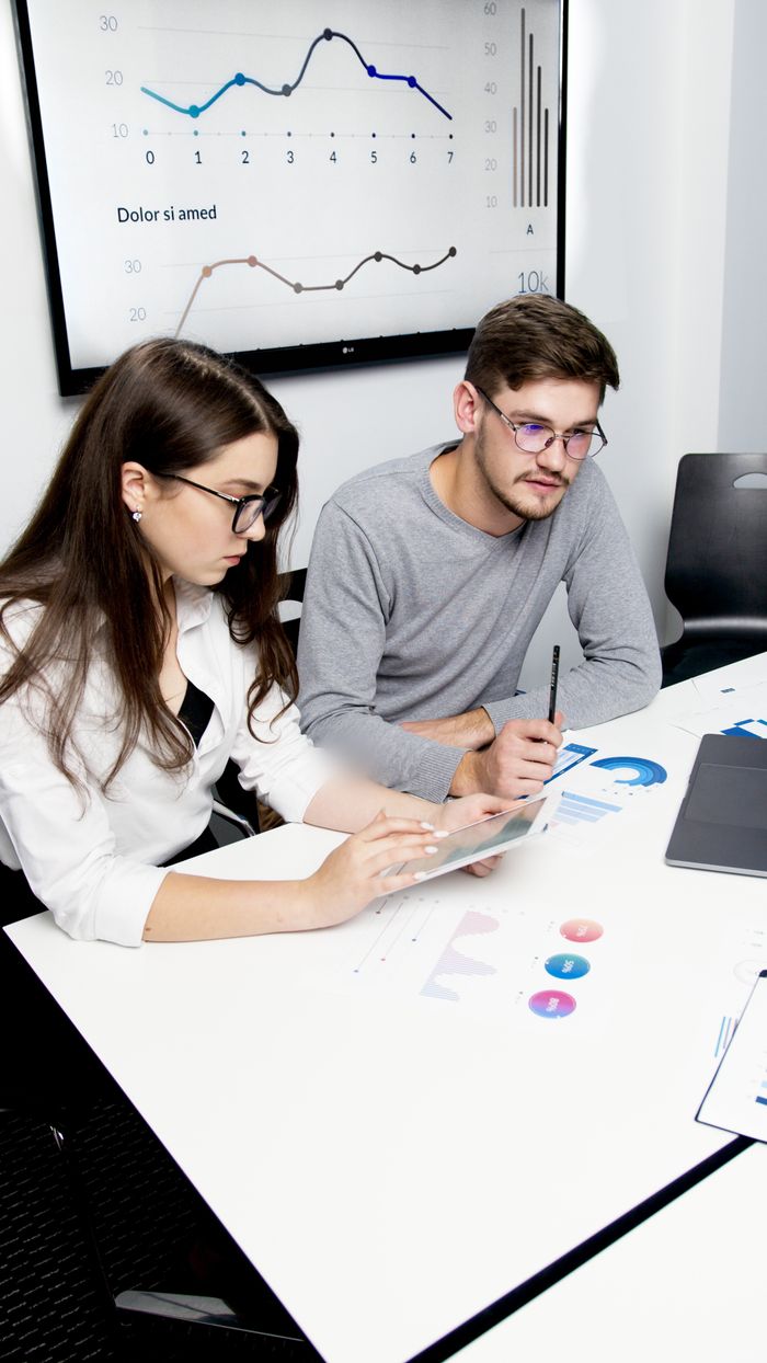About Two business professionals collaborating on financial analysis with charts and graphs.