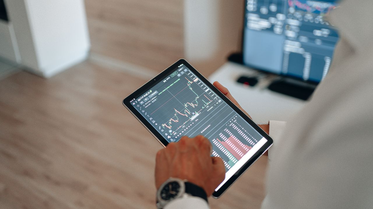 Home Close-up of hands using a tablet for online trading and market analysis.